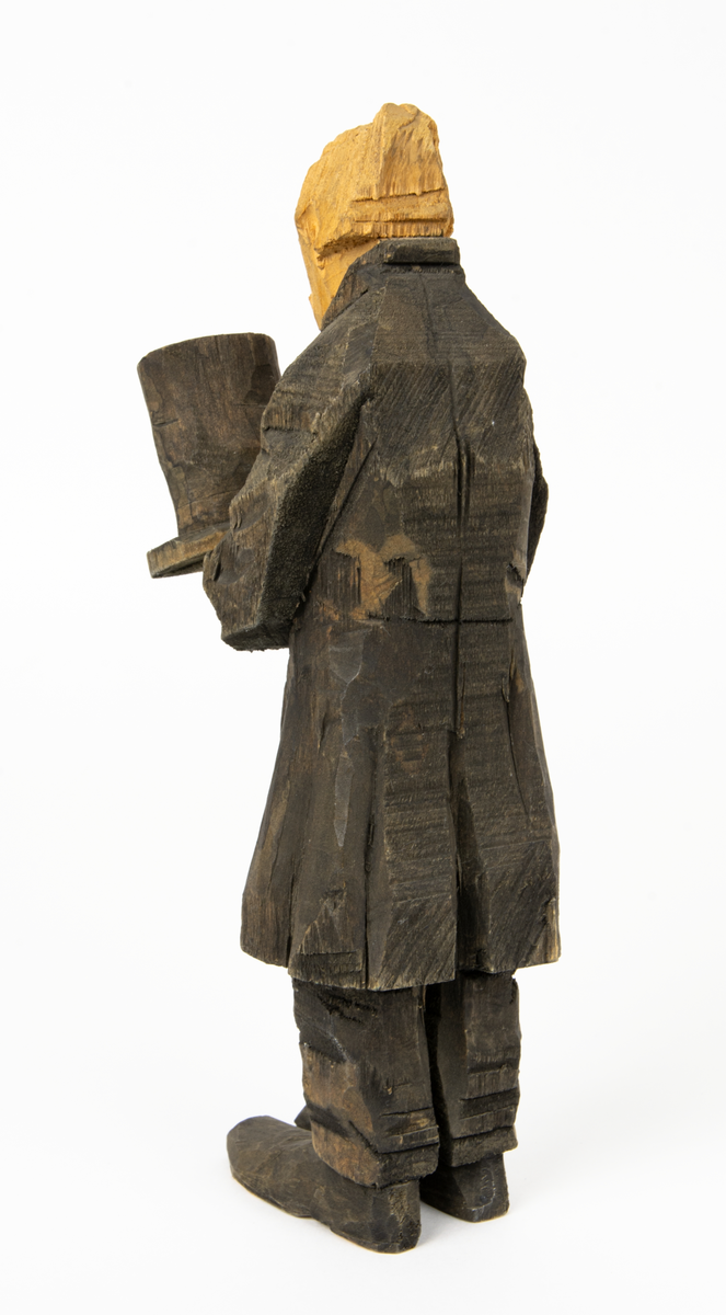 Skulpturgrupp "Begravningen", bestående av 8 objekt föreställande 6 män en präst, en kvinna samt en kista på bockar. 
Gruppens figurer: 
1. Dödgrävare Hultgren i rock och med hatt i handen. H 256 mm.
2. Svartklädd bärare som håller en hatt. H 234 mm. 
3. Svartklädd bärare som håller en hatt. H 240 mm. 
4. Svartklädd bärare som håller en hatt. H 140 mm. 
5. Klockare Sjöström som håller en hatt. H 265 mm.
6. Prosten Arbman med mantelsläpet runt ena armen. I vänstra hande håller han en uppslagen bibel och i den andra skall han hålla en skopa (vilken saknas). H 272 mm.
7. Den sörjande änka i svart klänning och schal och vit näsduk. H 238 mm.
8. En kista på två bockar, L 290 mm.