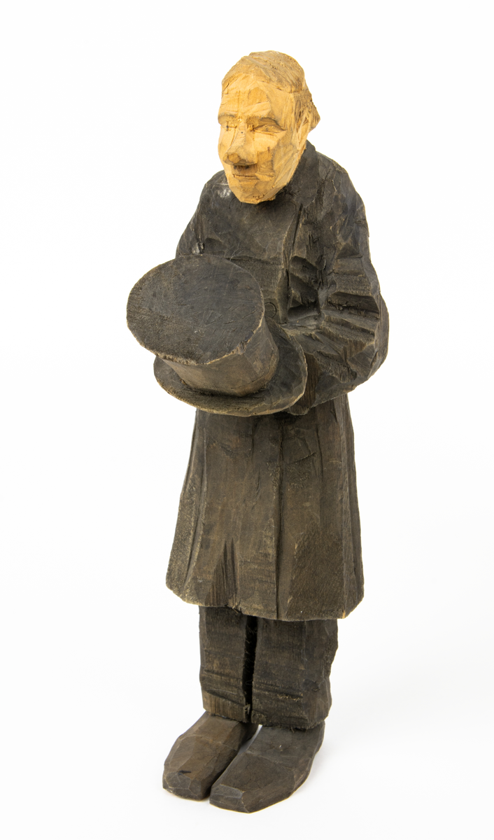 Skulpturgrupp "Begravningen", bestående av 8 objekt föreställande 6 män en präst, en kvinna samt en kista på bockar. 
Gruppens figurer: 
1. Dödgrävare Hultgren i rock och med hatt i handen. H 256 mm.
2. Svartklädd bärare som håller en hatt. H 234 mm. 
3. Svartklädd bärare som håller en hatt. H 240 mm. 
4. Svartklädd bärare som håller en hatt. H 140 mm. 
5. Klockare Sjöström som håller en hatt. H 265 mm.
6. Prosten Arbman med mantelsläpet runt ena armen. I vänstra hande håller han en uppslagen bibel och i den andra skall han hålla en skopa (vilken saknas). H 272 mm.
7. Den sörjande änka i svart klänning och schal och vit näsduk. H 238 mm.
8. En kista på två bockar, L 290 mm.