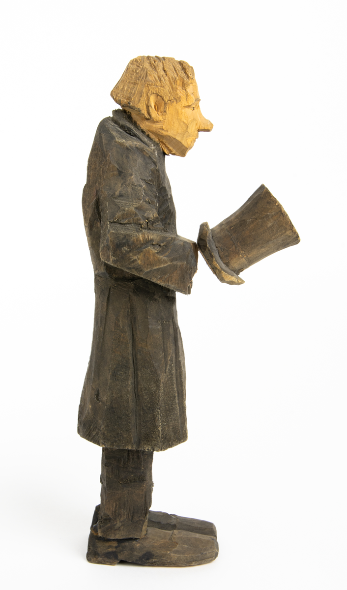 Skulpturgrupp "Begravningen", bestående av 8 objekt föreställande 6 män en präst, en kvinna samt en kista på bockar. 
Gruppens figurer: 
1. Dödgrävare Hultgren i rock och med hatt i handen. H 256 mm.
2. Svartklädd bärare som håller en hatt. H 234 mm. 
3. Svartklädd bärare som håller en hatt. H 240 mm. 
4. Svartklädd bärare som håller en hatt. H 140 mm. 
5. Klockare Sjöström som håller en hatt. H 265 mm.
6. Prosten Arbman med mantelsläpet runt ena armen. I vänstra hande håller han en uppslagen bibel och i den andra skall han hålla en skopa (vilken saknas). H 272 mm.
7. Den sörjande änka i svart klänning och schal och vit näsduk. H 238 mm.
8. En kista på två bockar, L 290 mm.