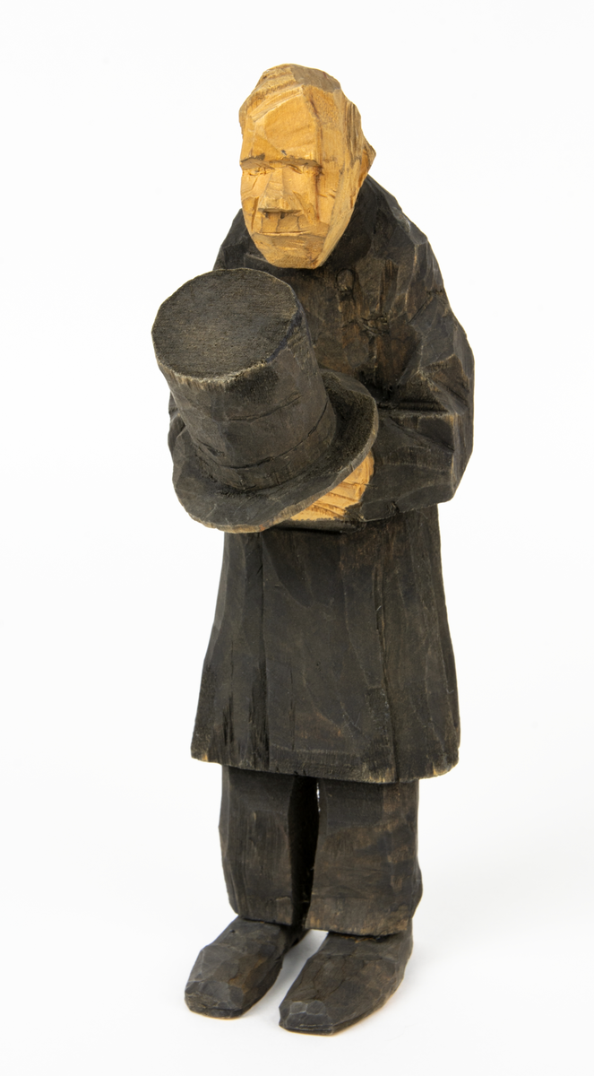 Skulpturgrupp "Begravningen", bestående av 8 objekt föreställande 6 män en präst, en kvinna samt en kista på bockar. 
Gruppens figurer: 
1. Dödgrävare Hultgren i rock och med hatt i handen. H 256 mm.
2. Svartklädd bärare som håller en hatt. H 234 mm. 
3. Svartklädd bärare som håller en hatt. H 240 mm. 
4. Svartklädd bärare som håller en hatt. H 140 mm. 
5. Klockare Sjöström som håller en hatt. H 265 mm.
6. Prosten Arbman med mantelsläpet runt ena armen. I vänstra hande håller han en uppslagen bibel och i den andra skall han hålla en skopa (vilken saknas). H 272 mm.
7. Den sörjande änka i svart klänning och schal och vit näsduk. H 238 mm.
8. En kista på två bockar, L 290 mm.