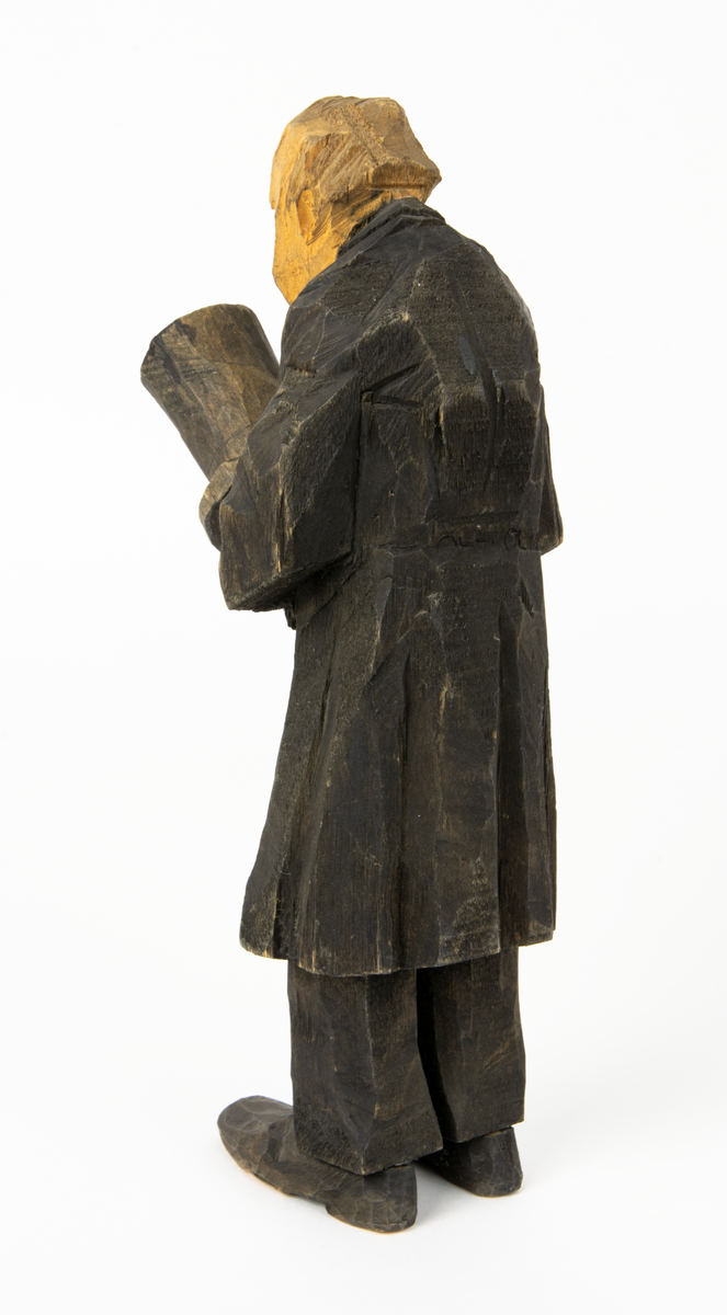 Skulpturgrupp "Begravningen", bestående av 8 objekt föreställande 6 män en präst, en kvinna samt en kista på bockar. 
Gruppens figurer: 
1. Dödgrävare Hultgren i rock och med hatt i handen. H 256 mm.
2. Svartklädd bärare som håller en hatt. H 234 mm. 
3. Svartklädd bärare som håller en hatt. H 240 mm. 
4. Svartklädd bärare som håller en hatt. H 140 mm. 
5. Klockare Sjöström som håller en hatt. H 265 mm.
6. Prosten Arbman med mantelsläpet runt ena armen. I vänstra hande håller han en uppslagen bibel och i den andra skall han hålla en skopa (vilken saknas). H 272 mm.
7. Den sörjande änka i svart klänning och schal och vit näsduk. H 238 mm.
8. En kista på två bockar, L 290 mm.
