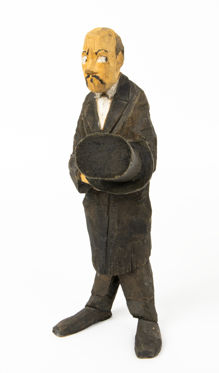 Skulpturgrupp "Begravningen", bestående av 8 objekt föreställande 6 män en präst, en kvinna samt en kista på bockar. 
Gruppens figurer: 
1. Dödgrävare Hultgren i rock och med hatt i handen. H 256 mm.
2. Svartklädd bärare som håller en hatt. H 234 mm. 
3. Svartklädd bärare som håller en hatt. H 240 mm. 
4. Svartklädd bärare som håller en hatt. H 140 mm. 
5. Klockare Sjöström som håller en hatt. H 265 mm.
6. Prosten Arbman med mantelsläpet runt ena armen. I vänstra hande håller han en uppslagen bibel och i den andra skall han hålla en skopa (vilken saknas). H 272 mm.
7. Den sörjande änka i svart klänning och schal och vit näsduk. H 238 mm.
8. En kista på två bockar, L 290 mm.