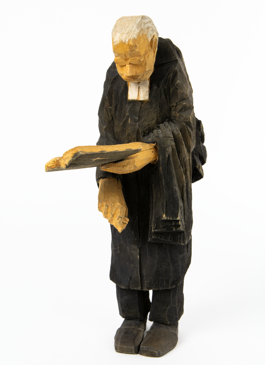 Skulpturgrupp "Begravningen", bestående av 8 objekt föreställande 6 män en präst, en kvinna samt en kista på bockar. 
Gruppens figurer: 
1. Dödgrävare Hultgren i rock och med hatt i handen. H 256 mm.
2. Svartklädd bärare som håller en hatt. H 234 mm. 
3. Svartklädd bärare som håller en hatt. H 240 mm. 
4. Svartklädd bärare som håller en hatt. H 140 mm. 
5. Klockare Sjöström som håller en hatt. H 265 mm.
6. Prosten Arbman med mantelsläpet runt ena armen. I vänstra hande håller han en uppslagen bibel och i den andra skall han hålla en skopa (vilken saknas). H 272 mm.
7. Den sörjande änka i svart klänning och schal och vit näsduk. H 238 mm.
8. En kista på två bockar, L 290 mm.