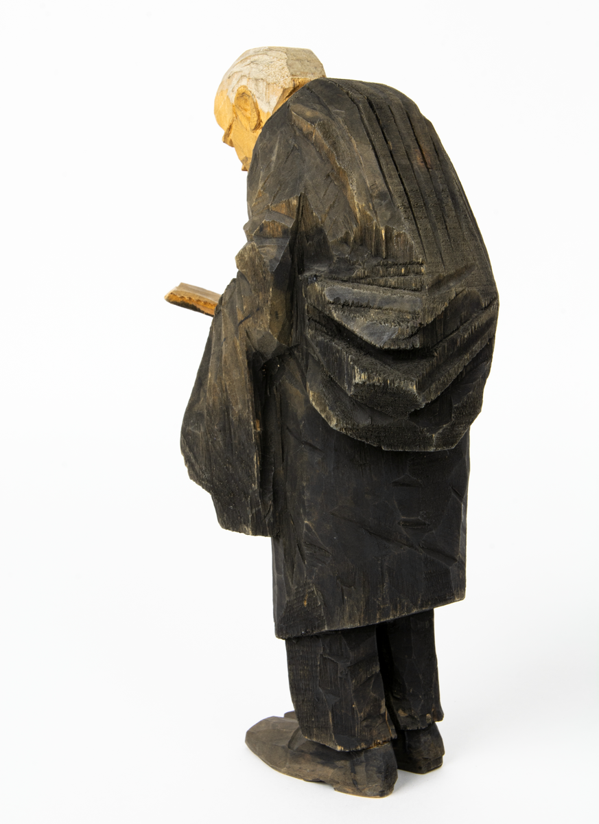 Skulpturgrupp "Begravningen", bestående av 8 objekt föreställande 6 män en präst, en kvinna samt en kista på bockar. 
Gruppens figurer: 
1. Dödgrävare Hultgren i rock och med hatt i handen. H 256 mm.
2. Svartklädd bärare som håller en hatt. H 234 mm. 
3. Svartklädd bärare som håller en hatt. H 240 mm. 
4. Svartklädd bärare som håller en hatt. H 140 mm. 
5. Klockare Sjöström som håller en hatt. H 265 mm.
6. Prosten Arbman med mantelsläpet runt ena armen. I vänstra hande håller han en uppslagen bibel och i den andra skall han hålla en skopa (vilken saknas). H 272 mm.
7. Den sörjande änka i svart klänning och schal och vit näsduk. H 238 mm.
8. En kista på två bockar, L 290 mm.