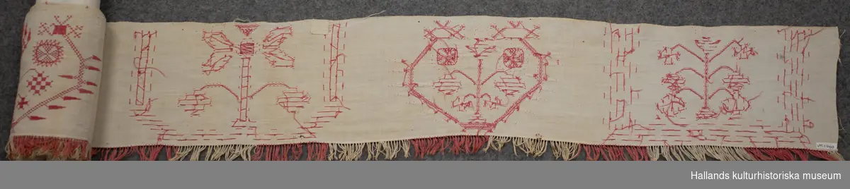 Hängkläde med frans. Vitt med broderier av bomullsgarn i rött och röd och vit frans.