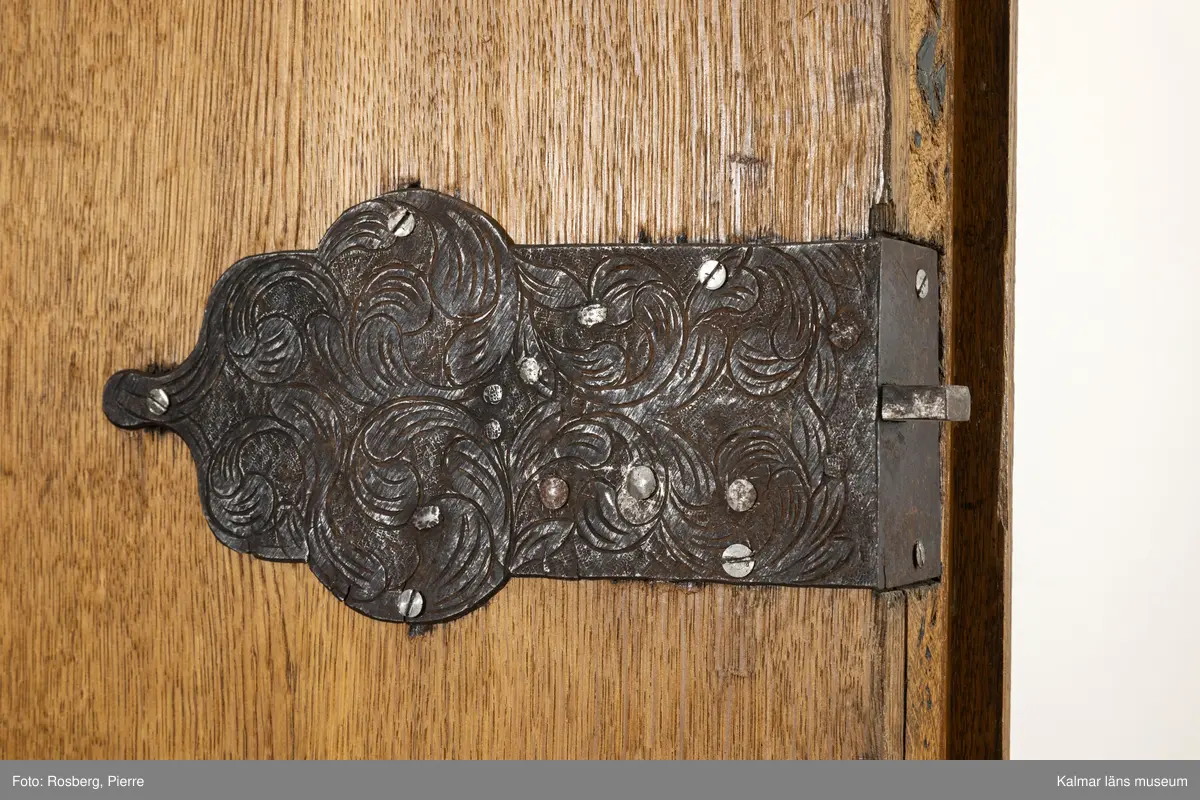 KLM 10106. Skåp. Stort ekskåp med dörrar och nedtill två lådor med handtag av metall i form av ring med blomformat beslag. Dörrarna med infällt lås, nyckelhålet kan på utsidan döljas med en del av listen som är skjutbar i sidled. Låsbeslaget på insidan av dörren har utmejslad dekor. Utskjutande krön. Tre kulfötter i front, baktill klossformade fötter. Skåpet är renoverat, bl.a. är hyllplan och bakstycke ej urspungliga.