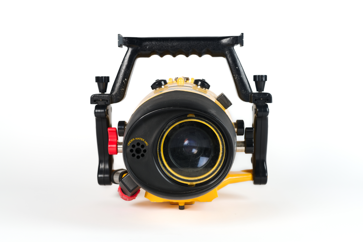 Videokamera i undervattenshus. Gult plasthölje, cylinderformat, med svarta vred och svarta handtag. Rött inspelningsvred samt röd elkontakt. Märkt: "Sony, 75 m Handycam Marine Pack." Dymolapp på höljet med text: "Koster". I höljet en videokamera i svart plast. "Sony Handycam", samt en monitor kopplad till materan med sladd: "Sony LCD Color Monitor XV-M30E". Monitorn synlig genom glaslucka i höljet. Höljet knäpps fast med tre knäpplås.