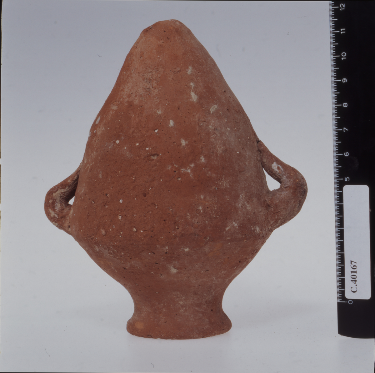 Amphoriskos with conical body, sloping shoulder and low curved neck with slightly splayed rim. Small handles at shoulderline.
EtnoNo: 39102. 
Samling: Ustinow-samling. Proveniens: H. Erichsen, J. Lejersted Bødtker, A. Rasstad 1940. 
Munsell: 10R5/8. MunsellSlip: 10R4/6. Farge: Red. ColourSlip: Red.
Bibliografi: I. Skupinska-Loevset, The Ustinow Collection. The Palestinian Pottery, Oslo etc. 1976, cat. UP 176.
<GMLPLASS>Pottery box 37</GMLPLASS><MELLOMPLASS>se12/KO8</MELLOMPLASS><NYPLASS>Pakket i eske nr. 47</NYPLASS>
