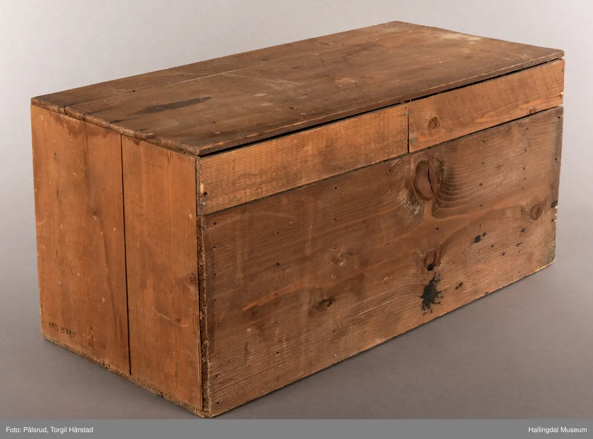 En liten skuffeseksjon i brunt tre med 17 skuffer i to rader. Hver skuff er oppdelt til å oppbevare bunker med frimerker, og har en liten sort metallknatt midt på framsiden av hver skuff som fungerer som håndtak. 