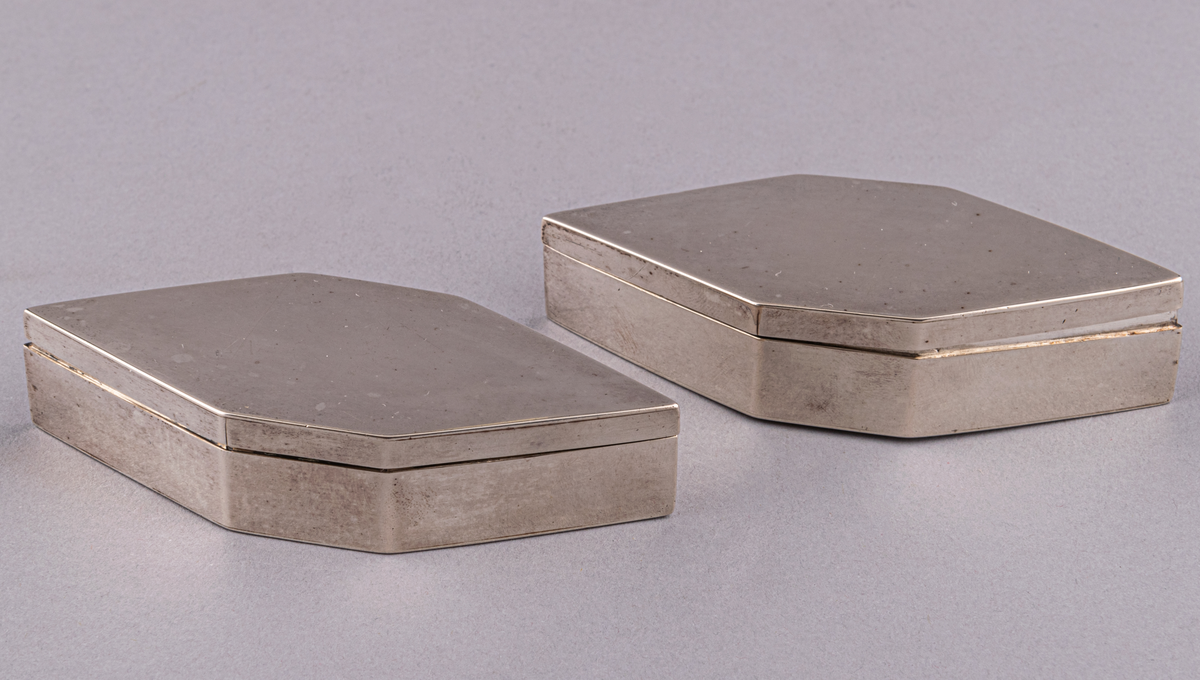 Silverdosor, 2st, sexkantiga. Lock utan gångjärn.
Helt utan ornamentik. Stämplar i dosornas botten och i locken: P2, G, kattfot, POB (=P.O. Bäckström 1821). Pehr Olof Bäckström 1812-1834.
L 10cm, BR 4,1cm, H 2cm (med lock). Lockets H 0,6cm.