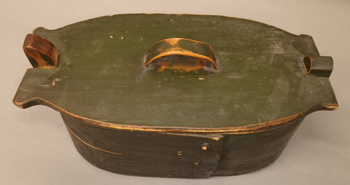 Oval tine i tre. Sveipa og sauma saman, med lok. Bunn og sider festet til hverandre med treplugger. Inni lokket er det ripa inn bokstavane: GJHS.