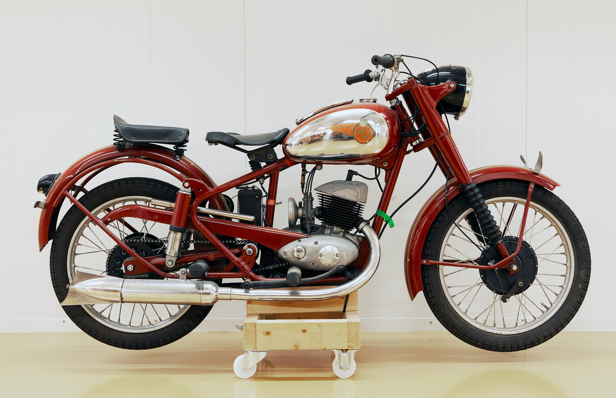 Motorcykel, modell NV 35, 250 kubik, årsmodell 1952. DKV-motor på 11,5 hästkrafter, tre växlar. Mörkt rödlackerad med guldränder på stänkskärmarna. Förnicklade detaljer. Bensintanken rödlackerad med förnicklat parti på båda sidorna med vingmärke i rött och guld med riksäpple och bokstäverna NV. På motorn i relief: DKW. På bensintankens förnicklade lock text: Använd Mobiloil från Vakuum Oil Company. Batteri NOAK svart gult och rött. Generator märkt HELLA, Germany. Svartlackerad stor lykta fram med hastighetsmätare, svartlackerad baklykta. Svart stor gummisadel, sits bakom av svart läder. Svarta gummihandtag på styret och svarta gummipedaler.  Svarta däck med svarta nav. Förnicklad cykelpump. Rödlackerat stöd.  Hållare för registreringskyltar.