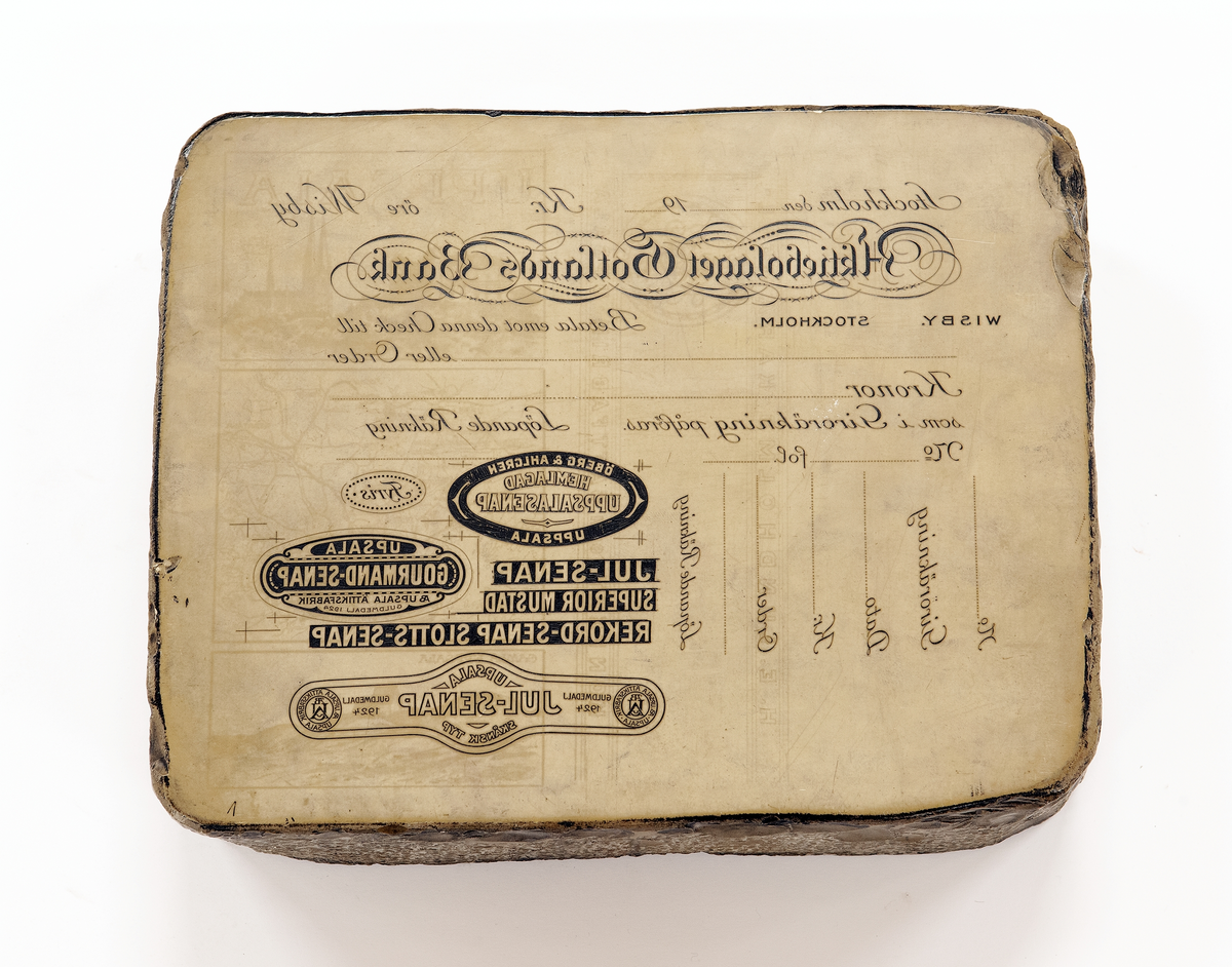 Litografisk sten med reklam för bl.a. Slotts rekordsenap, Uppsala-Ekeby AB och August Johanssons skoaffär.
Avdrag på papper.