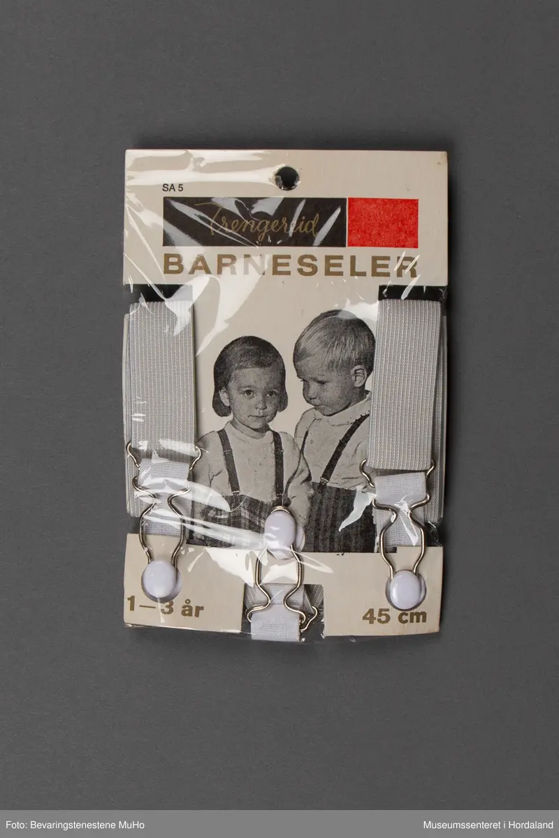 Bukseseler med grips i metall. Innpakning i plast og papp med svart/hvitt foto. Motiv: Gutt/jente, logo på svart bunn med gullskrift.