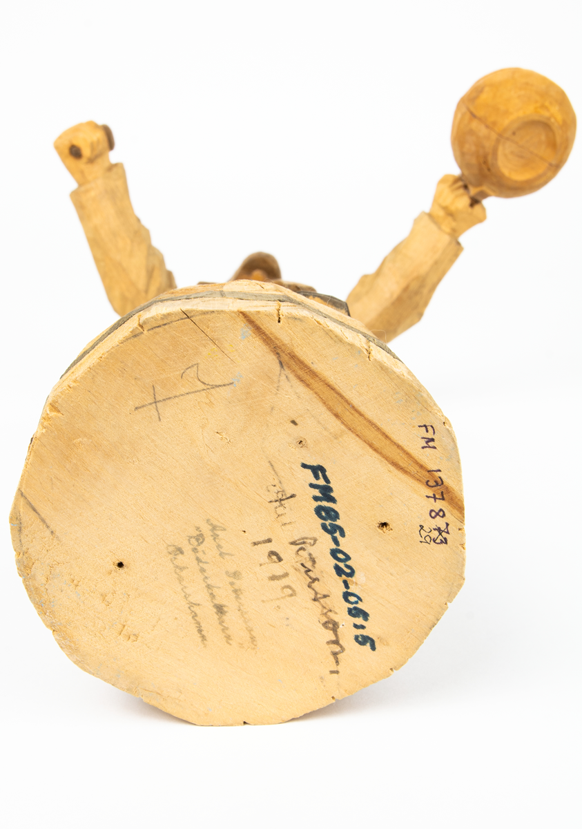 Auktion, skulpturgrupp föreställande sex personer som lyssnar till en auktionist. 
Figurer:
1. Man med händerna i fickorna, randig rock och rutiga byxor, pälsmössa. H 282 mm. 
2. Man med rock och pälsmössa. H 283 mm. 
3. Man med hatt och rock. I handen håller han ett par stövlar, H 274 mm. 
4. Kvinna insvept i schal. Hon håller ett klädesplagg, l 268 mm. 
5. Kvinna med schal och lång kjol. Hon håller ett klädesplagg, H 264 mm.
6. Kvinna insvept i schal.
7. Auktionist, "Ropar-Olle", som håller upp en potta. Den andra handen håller en klubba. Han står på en upp och nedvänd tunna.