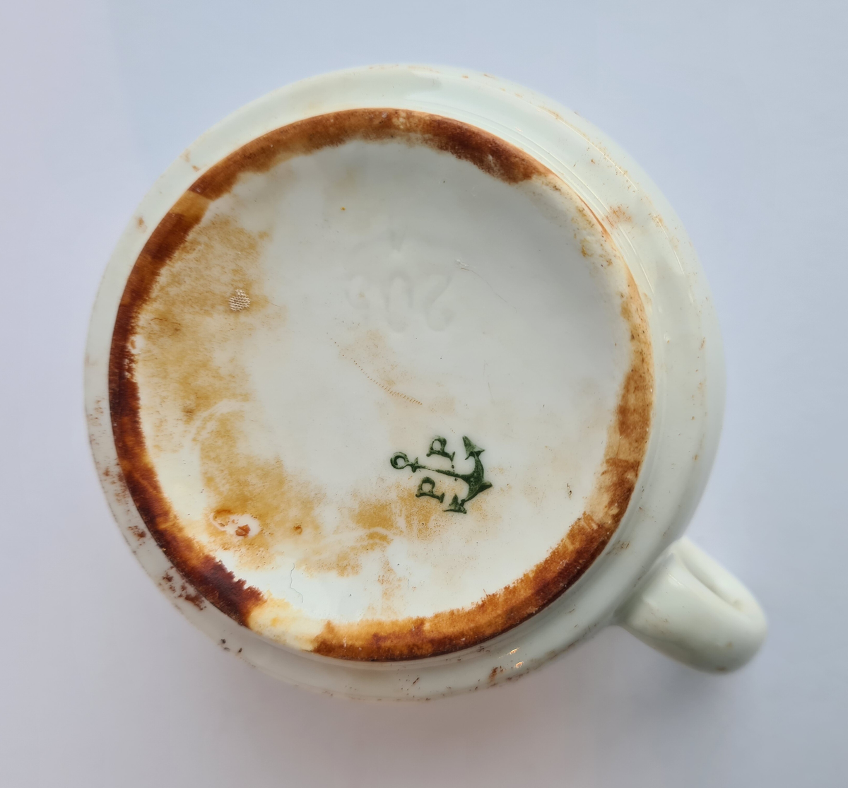 Lav, rund kaffekopp med hank av hvitt porselen.