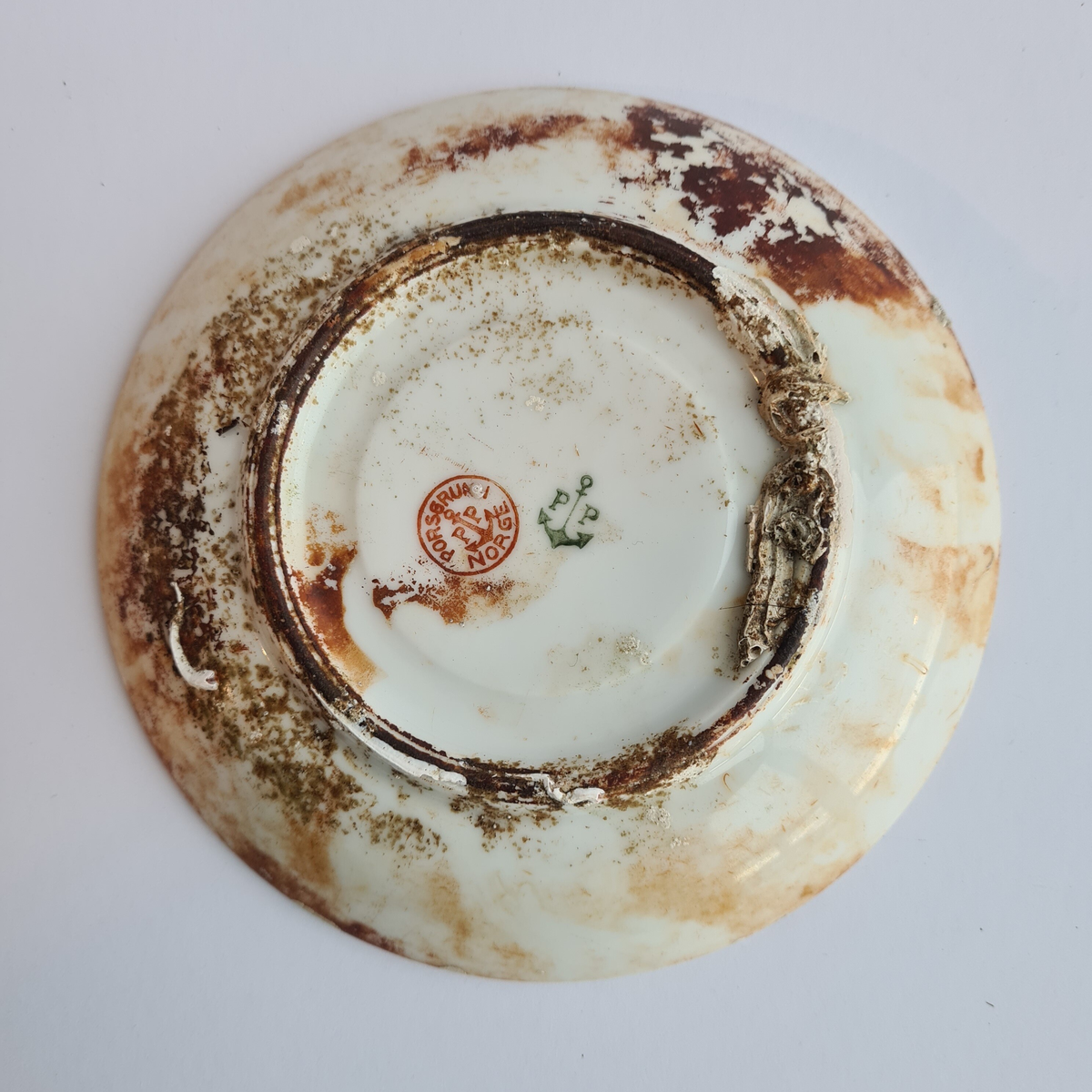 Kaffeskål av hvitt porselen merket "Det Stavangerske Dampskibsselskab" med to rederiflagg.
