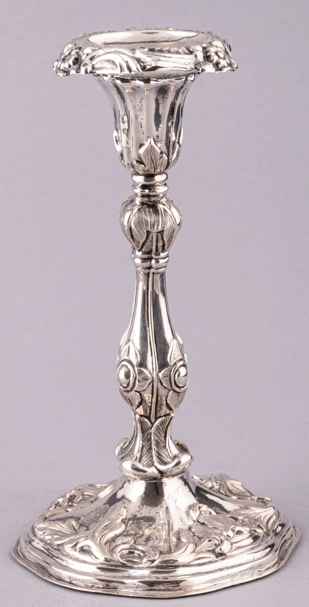 Ljusstake, silver. Vågig fot med växtornament.
Ljuspipan är försedd med växtornamnet.
Stake (a) och pipa (b) stämplad med bl.a. kattfot.
Stil nyrokoko.
Stockholm 1845. Gustaf Möllenborg.
Ingår i ett par.
