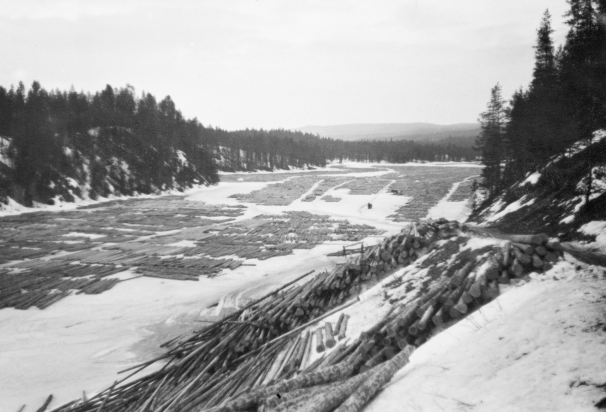 Tømmertillegging på Vesle-Osen, i Søre Osen i Trysil kommune i Hedmark. Fotografiet skal være tatt vinteren 1938. Det viser hvordan et tømmerparti var lagt i såkalte flakvelter på den snødekte isflata. Flakveltene besto av ett lag tømmerstokker som lå parallelt, men vinkelrett på to underlagsstokker. Underlagsstokkene skulle forebygge at tømmeret frøs ned i is og ble altfor fuktmettete etter eventuelle perioder med overvann. Fordelen ved denne tilleggingsmåten var at tømmeret ble veldig lett tilgjengelig for måling og merking. Her var det lett å se og kvalitetsvurdere hver enkelt stokk, med påfølgende «klaving» (diametermåling) og påslåing av kjøpermerker. Stokkene i flakveltene skulle ligge med de lengdemålene skogsarbeiderne hadde hogd på med romertall under apteringa oppovervendt, for å lette målernes arbeid. For å være noenlunde sikker på at tømmeret ikke ble altfor nedsnødd og nediset skulle det helst ikke legges tømmer i flakvelter for tidlig på vinteren. Til høyre i forgrunnen ser vi hvordan tømmer var blitt veltet av sledene fra en tømmerveg i en bratt skråning hvor det etter hvert kunne rulles ned mot strandlinja.