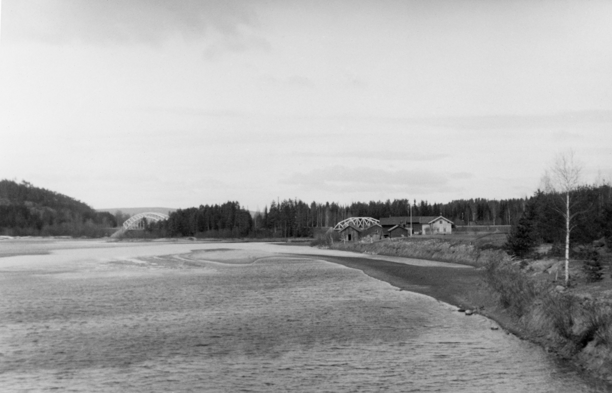 Landskapsfotografi fra Glomma like ovenfor Skjefstadfossen i Heradsbygda i Elverum i Hedmark. Fotografiet er tatt fra den østre elvebredden med kameraet vendt i motstrøms retning, riktignok på et sted der det var svært lite strøm. Opptaket er gjort en vårdag da det ennå var svært beskjeden vannføring. Vi ser en bratt elveskråning, ei rasflate der det knapt fantes vegetasjon. På litt distanse ser vi tunet på småbruket Fossum. Fossum-karene var fløterbaser på denne elvestrekningen, og de bygde robåter som ble brukt i denne virksomheten. Nordvest for Fossum ser vi den skogbevokste Haugsøya. Vi skimter også de to fagverksbruene der Solørbanen krysset elva via denne øya.