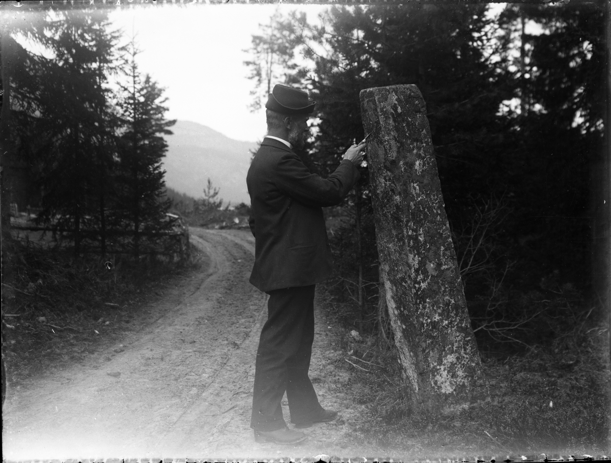 Fotosamling etter Bendik Ketilson Taraldlien (1863-1951) Fyresdal. Gårdbruker, fotograf og skogbruksmann. Fotosamlingen etter fotograf Taraldlien dokumenterer områdene Fyresdal og omegn. 
Portrett av Tarjei Lie ved Skeisteinen. Runesteinen på Molandsmoen.