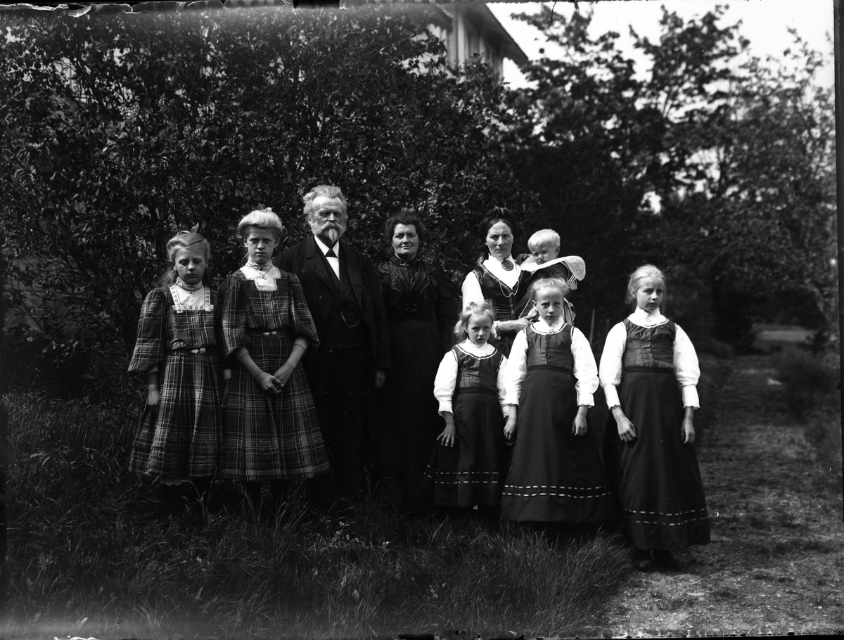 Fotosamling etter Bendik Ketilson Taraldlien (1863-1951) Fyresdal. Gårdbruker, fotograf og skogbruksmann. Fotosamlingen etter fotograf Taraldlien dokumenterer områdene Fyresdal og omegn. 
Gruppeportrett av familien Veum og Taraldlien i hagen på Taraldlien.