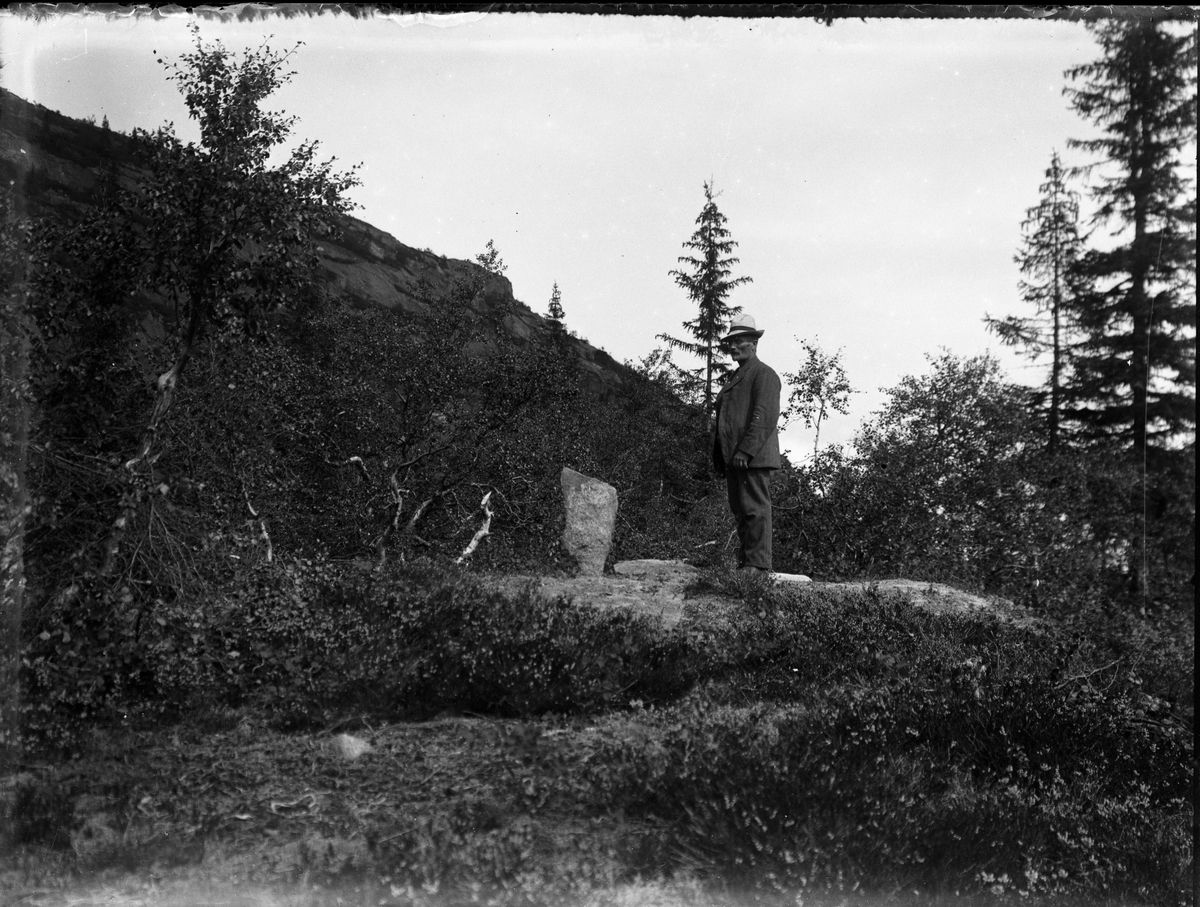 Fotosamling etter Bendik Ketilson Taraldlien (1863-1951) Fyresdal. Gårdbruker, fotograf og skogbruksmann. Fotosamlingen etter fotograf Taraldlien dokumenterer områdene Fyresdal og omegn. 
Portrett av Gunnar Sundbø ved merkestein i Birtedalen.
