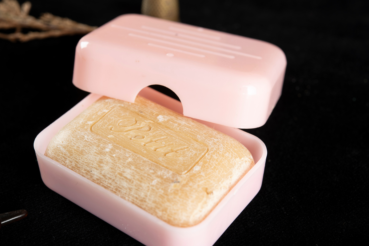 Träask med påklistrat, illustrerat motiv på ovansidan. Skrinet är låsbart, men beslaget är trasigt och metallen saknas över hålet. I bakkant sitter två små, enkla gånggärn. I skrinet förvaras flertalet minnessaker såsom enstaka knappar, spännen, löv, börs, armband, ljus, gräsvippa, ring, fingeborg och garnbollar.