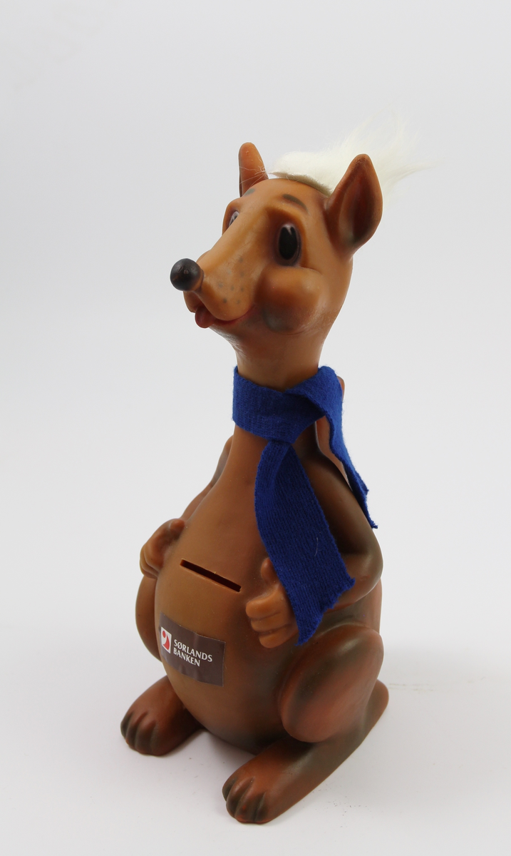 Sparebøsser i form av to plast figurerer og en glassbeholder. En kenguru med blått skjerf og hvitt hår, en dresskledt figur med gule hender, gult stort rundt hode og blått bakhode, en rektangulær glassbeholder med skrånede hjørner og metallokk.