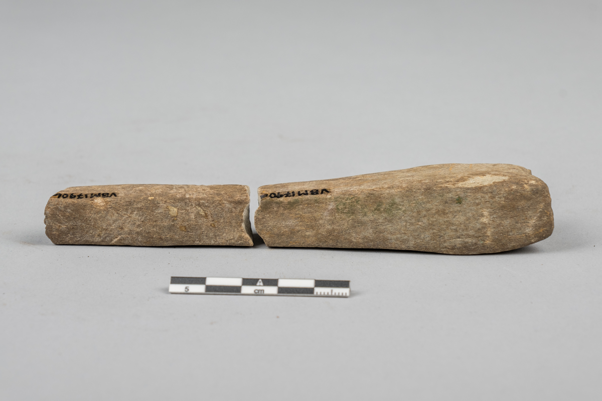 Bryne eller hein til sliping av redskaper. Brukket opp i flere deler. Kun to av delene inngår i samlingen. Resten er tapt. Firkantet tversnitt, bredere i ene enden.