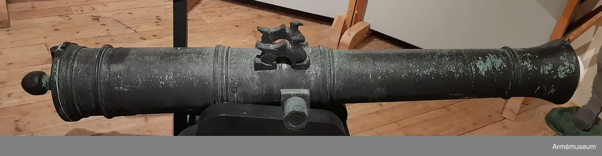 Med årtalet 1803 strax framför och inskriften: "St. Petersburg", å ryska, strax bakom delfinerna. (På den vänstra tappens fria ände: "No 97", på den högra tappens fria ände: "20 ny. 24 1/2 oy" - "20 Pud 24,5 Pund". Fängpannan har formen av ett manshuvud utan skägg, och befinner sig på bottenplanet. Delfinerna har formen av örnar. Strax framför kammarbandet finns präglat: "I. Wilson". v. Tepfers)