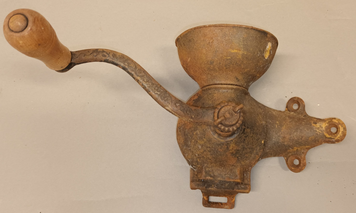 Til å feste på veggen med 3 skruvar. Sveiva er festa midt framme og har trehandtak. Oppsamlingskaret heng i botn og er til å ta av.