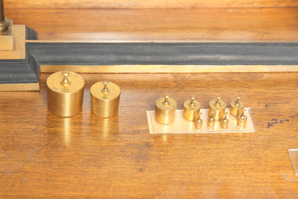 Spesialvekt, balansevekt a) og skap b). Vekten er av messing, og er gradert fra 0-100 gr. Skapet er av tre og glass med skuff for tilbehør. Antatt datering ca 1910, brukt ved Kapp Melkefabrikker og merket; Nestle No 168. Vekta er produsert av J. Richards Phil A/S.