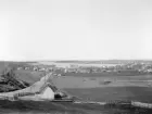 Panorama över Motala. Bilden är odaterad men kan med god lokalkännedom säkert preciseras närmare än vad vi här antar vara 1890-tal. Vy från sydost mot stadens bebyggelse runt Motalaviken. Till vänster landsvägen från söder som motsvarar den senare namngivna Sveavägen.