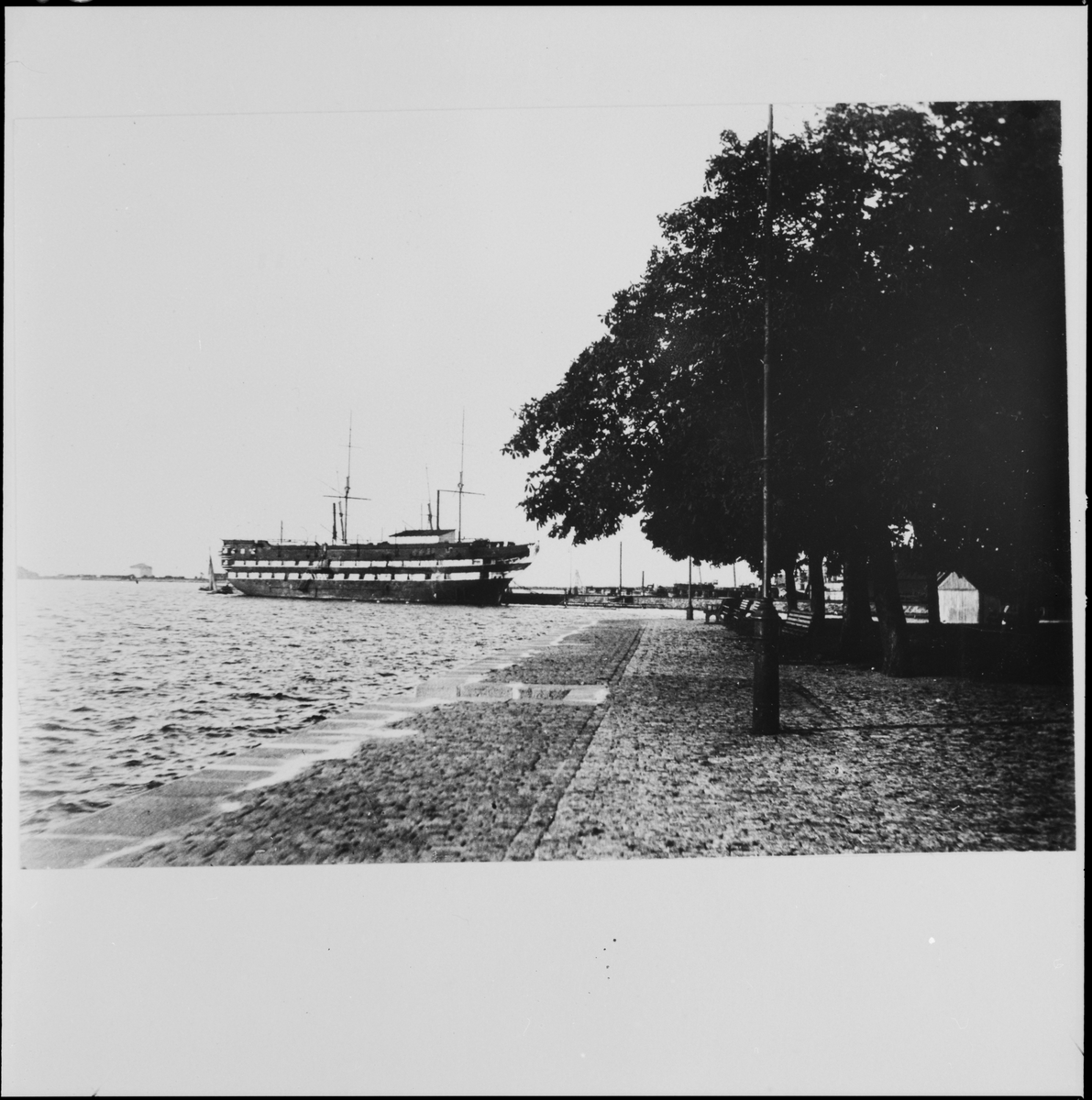 Bilden visar linjeskepp Stockholm nedriggad som logementsfartyg liggande vid s.k. polispiren i Karlskrona. I föregrund syns Tårarnaspark, Kungsbron vid Bastion Aurora.