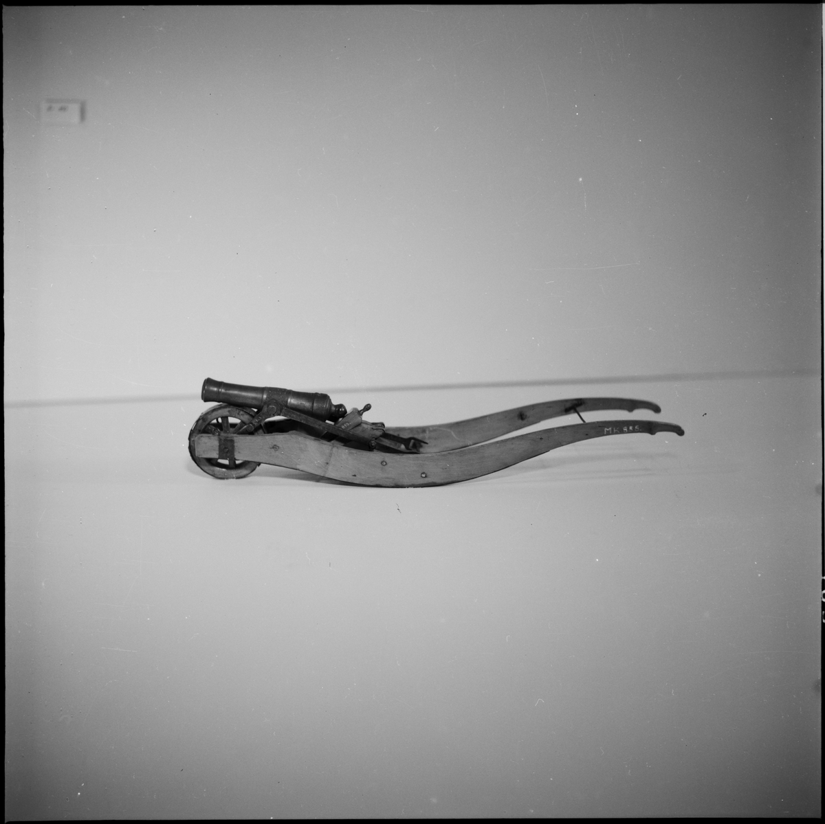 Modell av kanonskottkärra med 2-p metallnicka. Kärran av trä med järnbeslag. Nickan märkt "XII : IV". Tillbehör: 1 st riktkil. Troligen Chapman. Lavetten L = 350 mm B = 85 mm H = 85 mm.