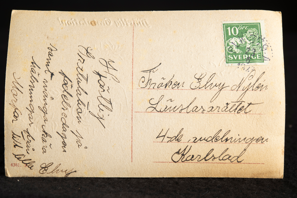 Ett dukat bord, rikt utsmyckat med bladgirland längs kanten av en mönstrad vit duk. Stor blombukett med orange- och rödtonade rosor i gråfärgat papper i vänstra delen, nedanför en bakad, mjuk kaka med vågmönster, samt strödda rosor. I mitten en kaffeservis i vitt porslin, med grön bård. Till höger på bordet ett fruktfat på fot i glas, med blandade frukter, och nedanför en liggande bukett i samma färger som tidigare.
I övre kanten står texten Hjärtlig Gratulation! i silver. Bakgrunden är svagt gråtonad.