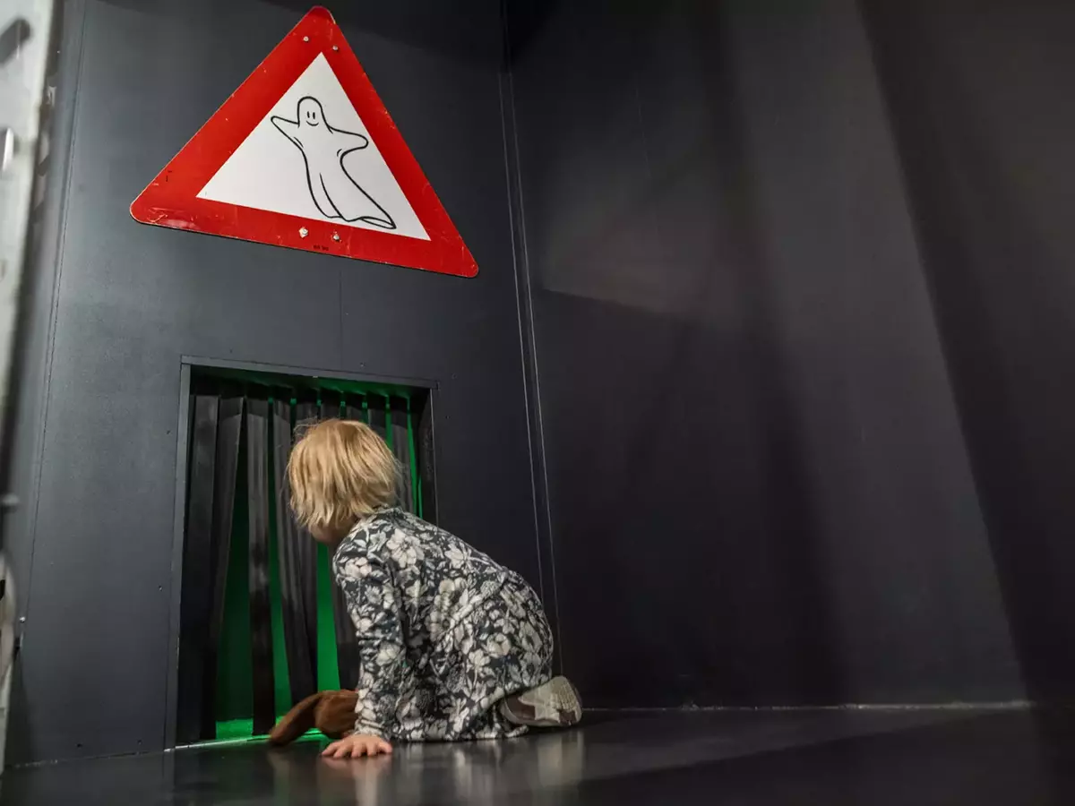 Bildet viser et barn på vei inn i Spøkelsestunnelen i utstillingen Drift.