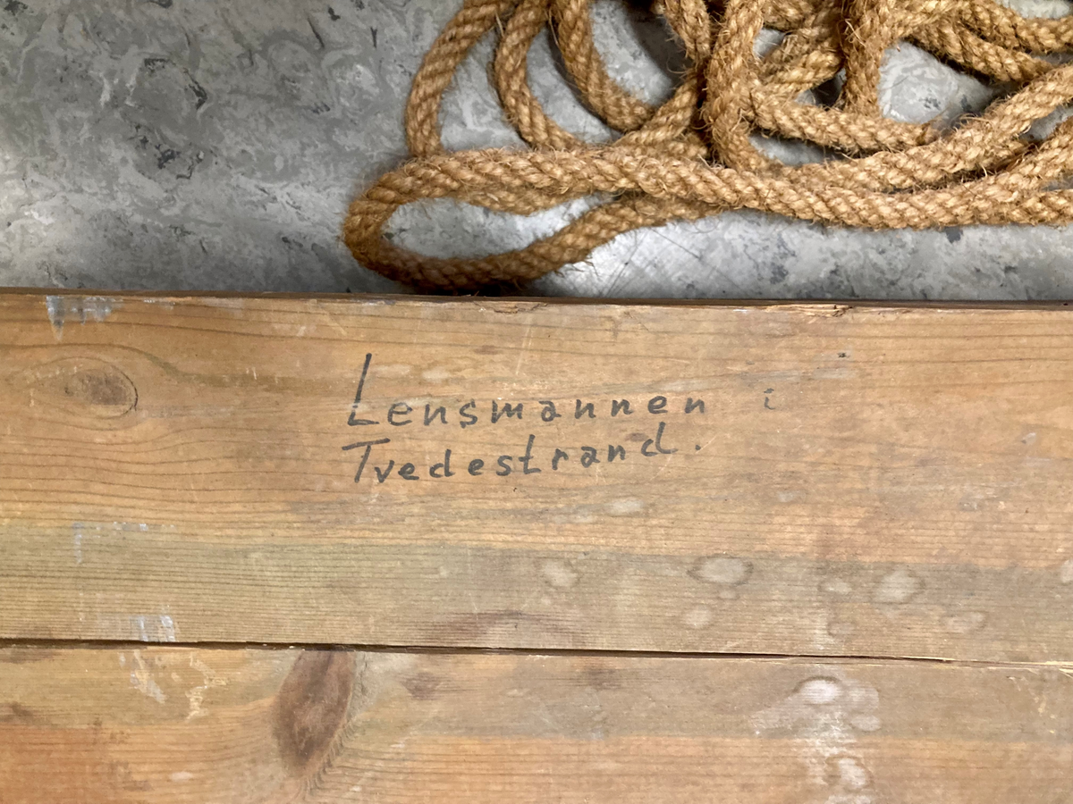 Dregg i metall. En metallstang med seks kraftige kroker, kjetting for taufeste. Oppbevaringsksse i tre. Tau i naturmateriale medfølger.