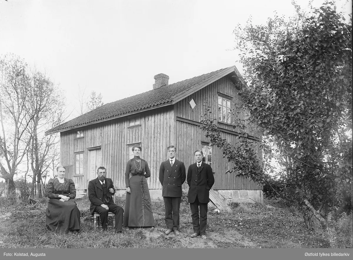 Gruppe fotografert i hagen utenfor våningshus. Ukjent sted og ukjent sted.