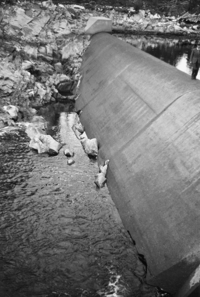 Terskeldammen ved Kvernfallet i elva Søndre Osa i Åmot kommune i Hedmark, fotografert i 1938, cirka to år etter at dette anlegget sto ferdig. Det dreier seg om en betongdam som var skrånet på «luftsida» og hadde avrundet krone. Denne dammen skulle stuve opp vann til turbinrøret som førte vann fra denne dammen til en kraftstasjon ved det nedenforliggende Brufallet. Da dette fotografiet ble tatt var dammen midlertidig tørrlagt.