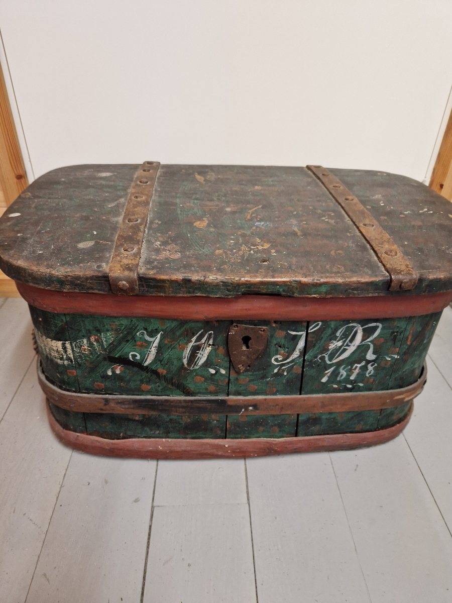 12 staver satt sammen med 3 treband, med bunn og lokk. 2 jernbeslag over lokket, og lås med nøkkel. Malt.