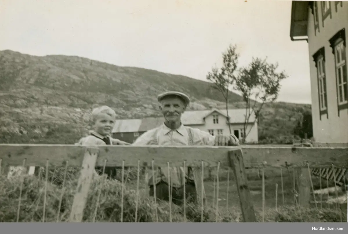 Innkjøring av tørrhøy på Lund i Leiranger. Hans Martin Korneliussen, født i 1879, står bak høyvogna. I vogna står barnebarnet Svein Erik Lieng. I bakgrunnen ser vi huset til Karl Lund.