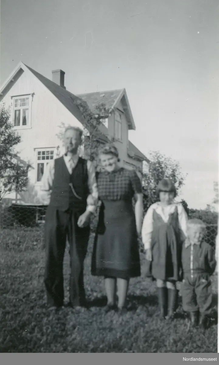 Familie som står utenfor huset sitt på Engeløya i Steigen. Kristian og Gudrun Zahl med barna Olga og Karl Fredrik.