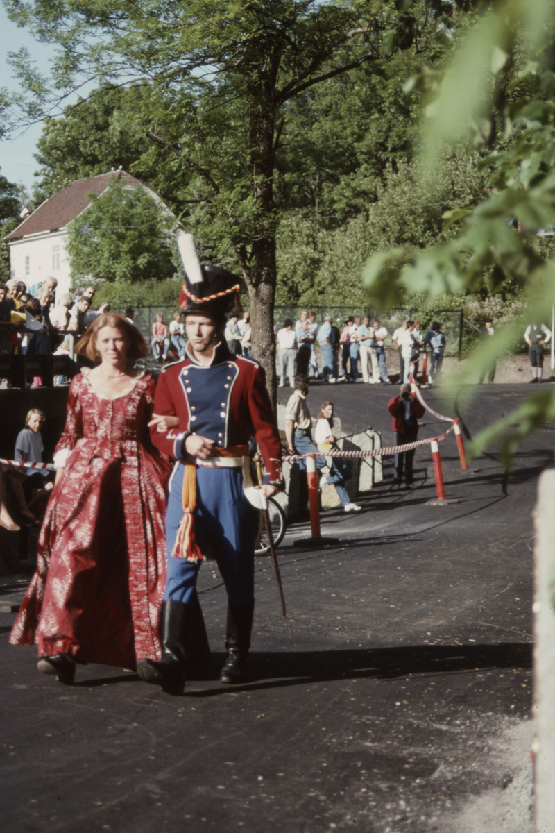 Kvinne i lang kjole mann i uniform
