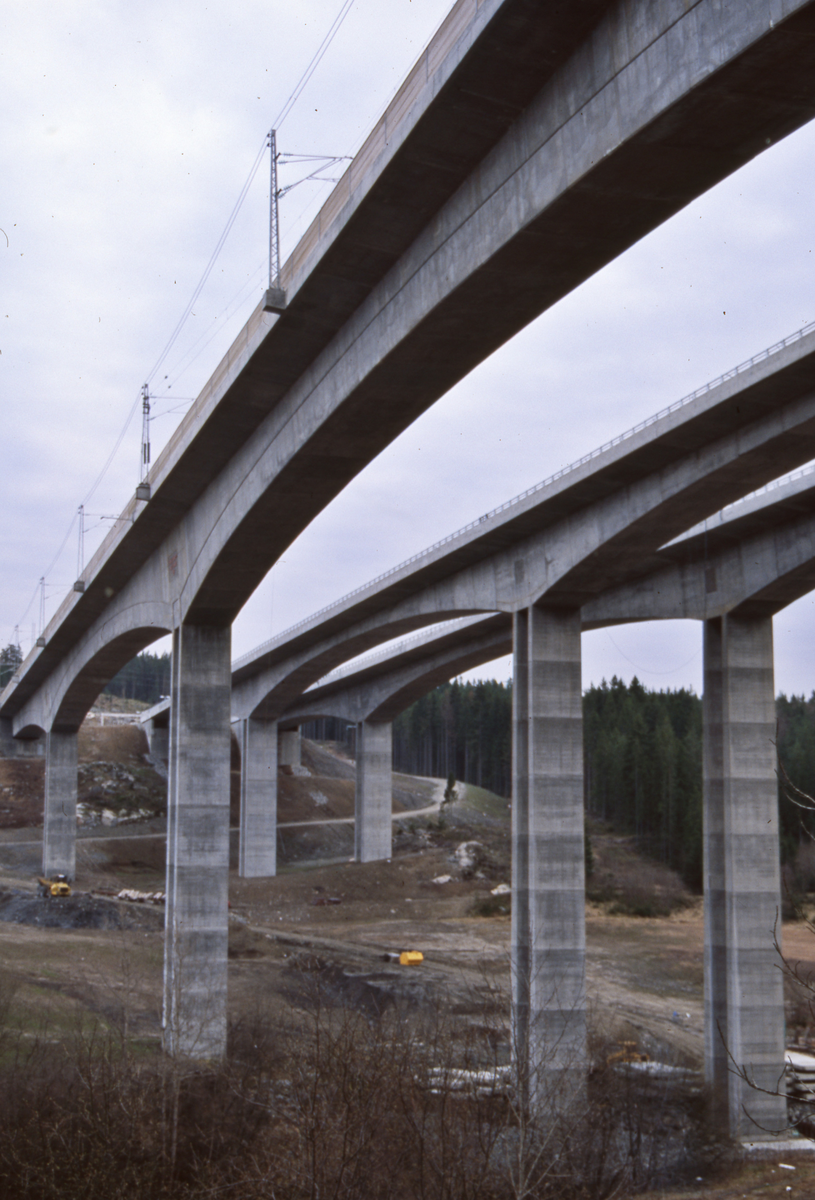 Hølendalen. Nye betongbruer for dobbelt-sporet jernbane (lengst øst/nærmest) og motorvei E6 under oppføring.  Veien ikke ferdig ennå. Jernbanebru l=416 m, h=50 m, spenn l=128m