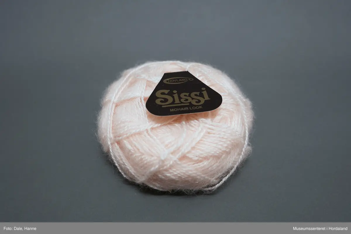 Eit rosa nøste Sissi garn i "mohair look", produsert ved Hovland Ullvarefabrikk. Garnet er ei blanding av akryl, polyamid, ull og mohair, og strikkast på pinne 3 1/2-4.