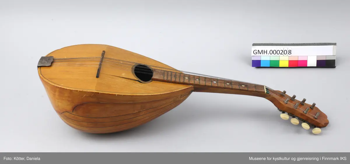 Mandolin med pæreformet resonanskasse, avvinklet lokk, en sterk hvelvet bunn, kort hals og åtte strenger. Instrumentet er produsert i Italia.