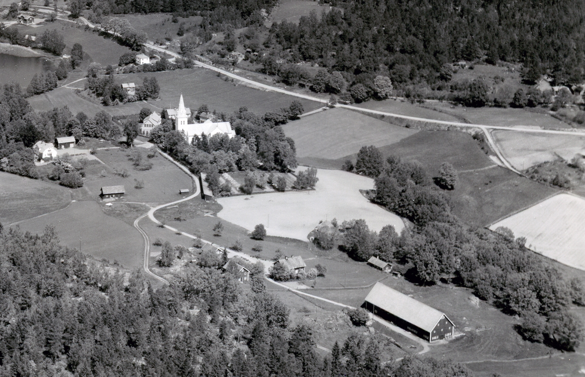 Dalhem med bebyggelse samt sjö och skog. Kyrkan framträder. Den ena bilden visar det obeskurna fotot, det andra beskärningen till vykort.