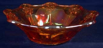 Skål av orange transparent glas med cirkelrund botten och mjukt utåtställda kanter. På bottens, tillika skålens undersida har ytan dekorationer i glaset i form av en stjärna och bladliknande former. På utsidans kanter finns dekorationer i ytan i form av stjärnor.
Diameter i botten: 84 mm.